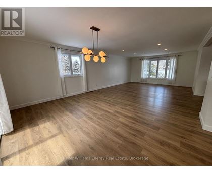 A spacious room with wooden flooring and a chandelier.