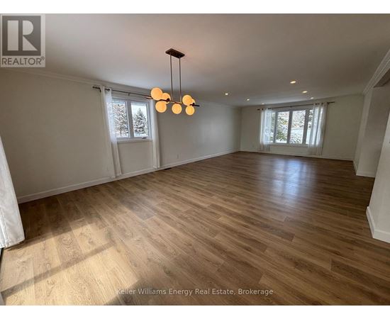 A spacious room with wooden flooring and a chandelier.