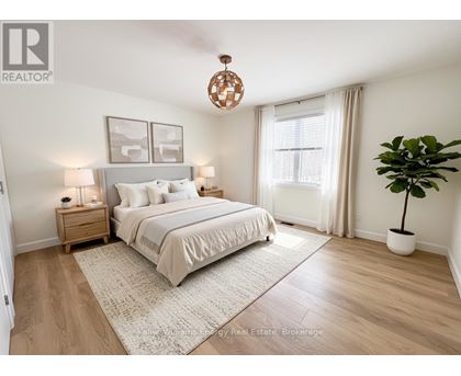 A bedroom with a large bed, a nightstand with a lamp, a window with curtains, and a potted plant.