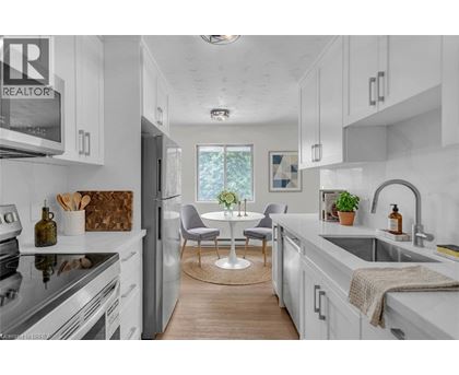 A modern kitchen with white cabinets and a wooden floor.