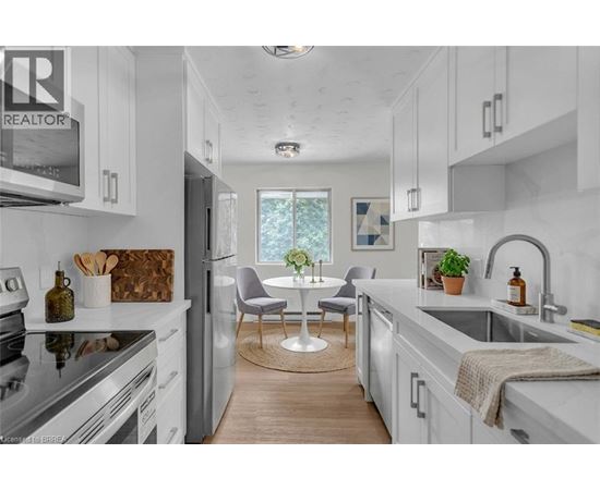 A modern kitchen with white cabinets and a wooden floor.