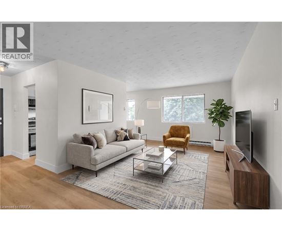 A living room with a grey couch, a brown armchair, a glass coffee table, a television, and a potted plant.