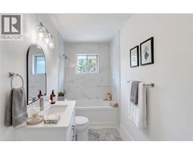 A white bathroom with a marble wall and a towel rack.