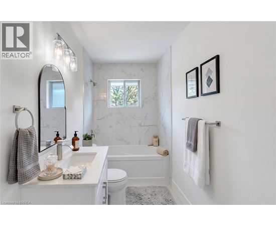 A white bathroom with a marble wall and a towel rack.
