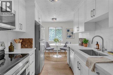 A modern kitchen with white cabinets and a wooden floor.