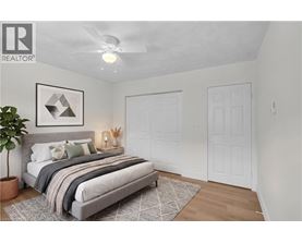 A bedroom with a bed, a plant, and a framed picture on the wall.