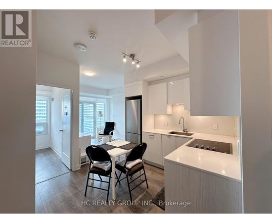 A modern kitchen with white cabinets and a dining table with four chairs.
