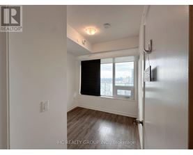 A white room with a window and a wooden floor.