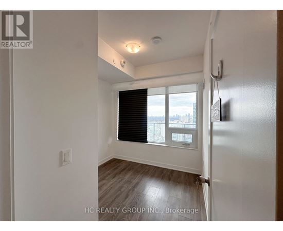 A white room with a window and a wooden floor.