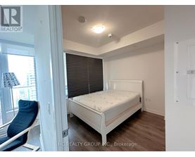 A bedroom with a white bed and a blue chair.