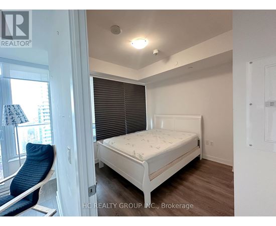 A bedroom with a white bed and a blue chair.