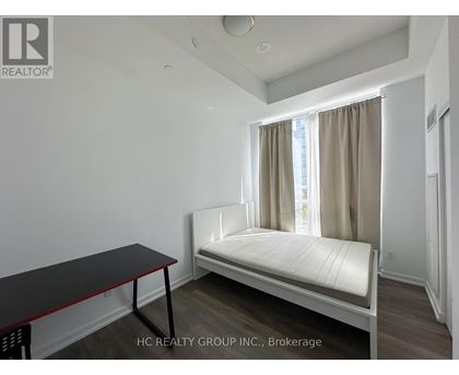 A bedroom with a bed, table, and window.