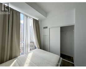 A bedroom with a large bed and a window with curtains.