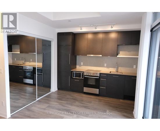 A modern kitchen with dark wood cabinets and stainless steel appliances.
