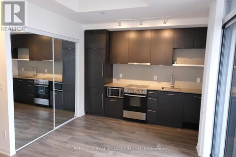 A modern kitchen with dark wood cabinets and stainless steel appliances.