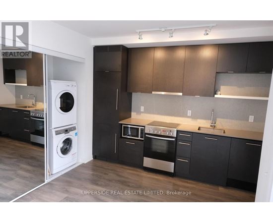 A modern kitchen with dark wood cabinets and stainless steel appliances.
