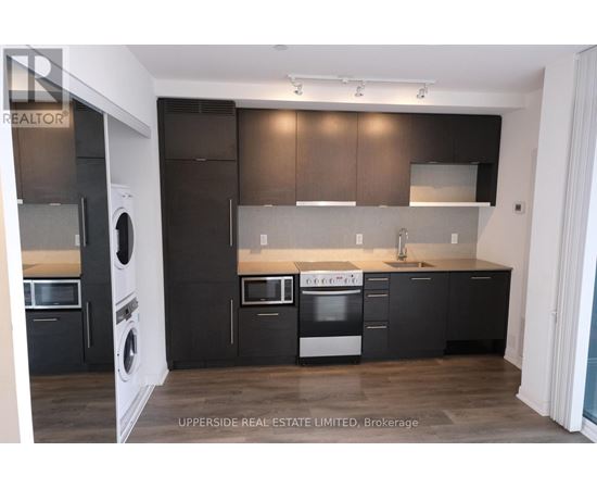 A modern kitchen with dark brown cabinets and stainless steel appliances.