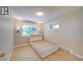 A bedroom with a bed, window, and a small picture window.