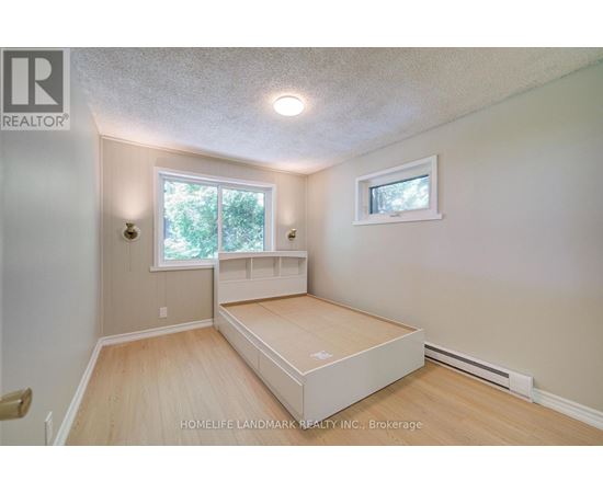 A bedroom with a bed, window, and a small picture window.