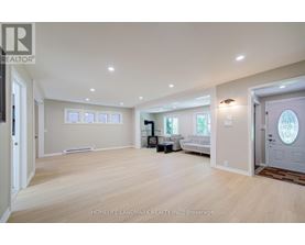 A spacious room with light wood flooring and white walls.