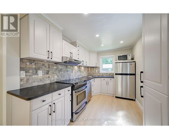 A kitchen with white cabinets and a black countertop.