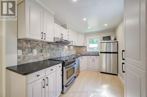 A kitchen with white cabinets and a black countertop.