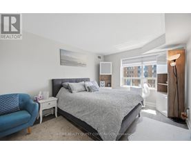A bedroom with a large bed and a blue chair.