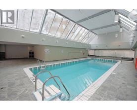 A swimming pool inside a building with a glass ceiling.