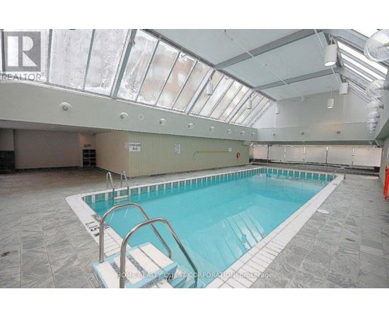 A swimming pool inside a building with a glass ceiling.