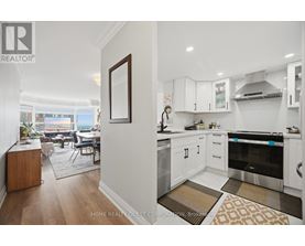 A modern kitchen with white cabinets and a wooden floor.