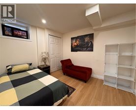 A bedroom with a bed, a red chair, and a painting on the wall.