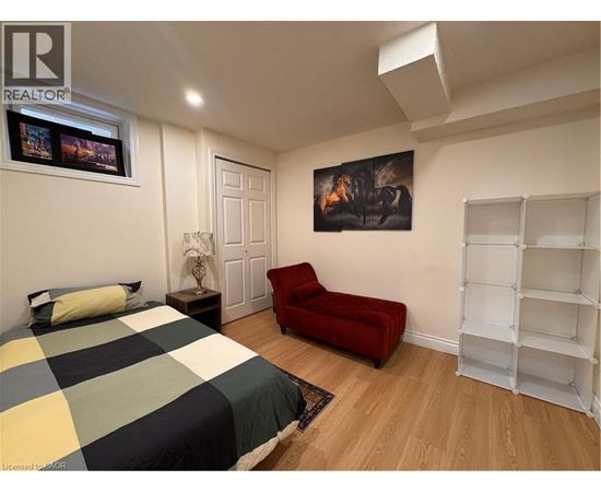 A bedroom with a bed, a red chair, and a painting on the wall.