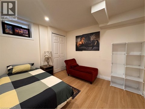 A bedroom with a bed, a red chair, and a painting on the wall.