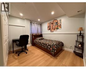 A bedroom with a bed, chair, and painting on the wall.