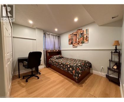 A bedroom with a bed, chair, and painting on the wall.