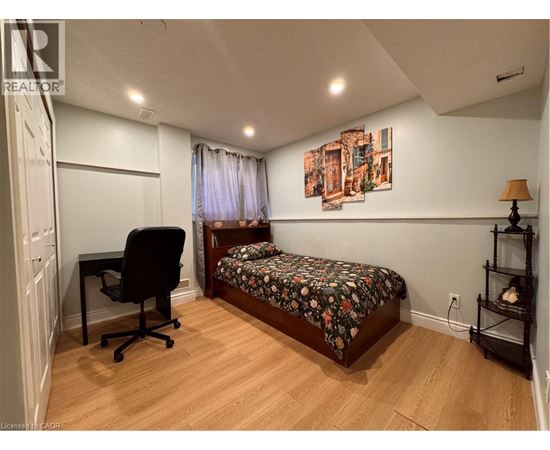 A bedroom with a bed, chair, and painting on the wall.