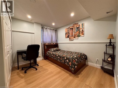 A bedroom with a bed, chair, and painting on the wall.