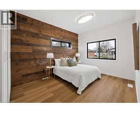 A bedroom with a white bed and a wooden wall.