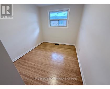 A room with wood flooring and a window showing a view of a building.