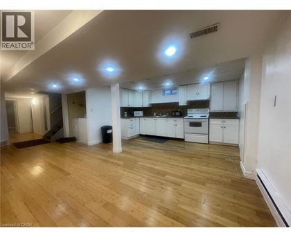 A spacious kitchen with white cabinets and a wooden floor.