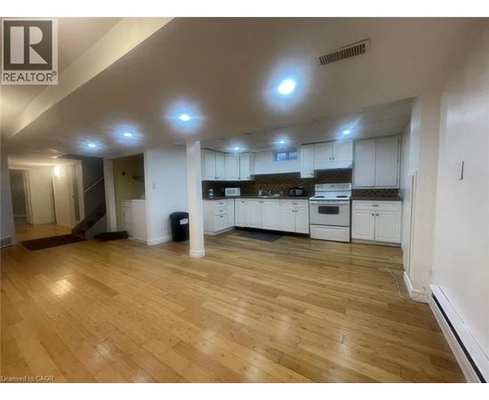 A spacious kitchen with white cabinets and a wooden floor.