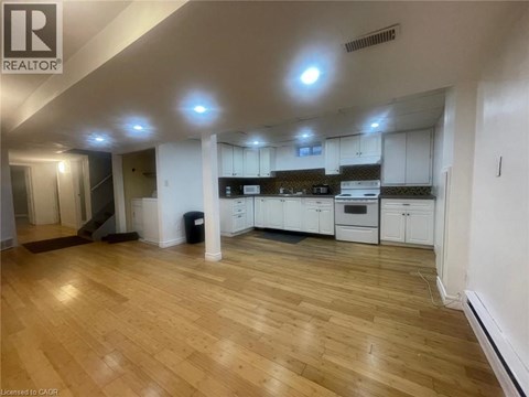 A spacious kitchen with white cabinets and a wooden floor.