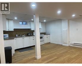 A well-lit, empty kitchen and living room with wooden floors and white walls.