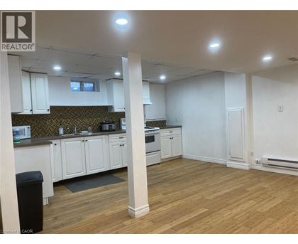 A well-lit, empty kitchen and living room with wooden floors and white walls.