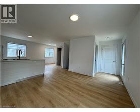 A spacious room with wooden flooring and white walls.