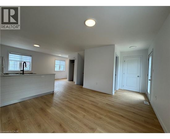 A spacious room with wooden flooring and white walls.