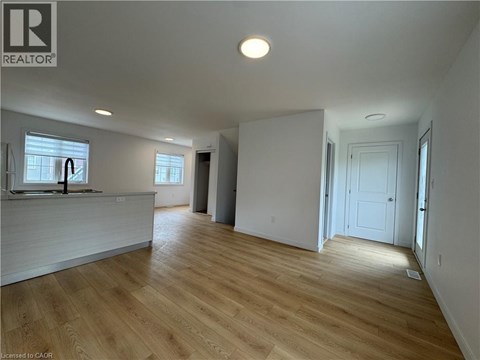 A spacious room with wooden flooring and white walls.