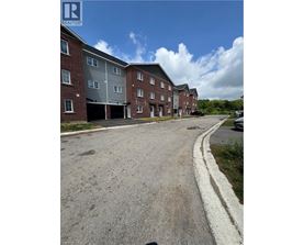 A large red brick apartment building with a parking lot in front.