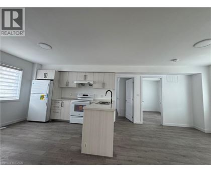 A well-lit kitchen with a refrigerator, oven, and sink.
