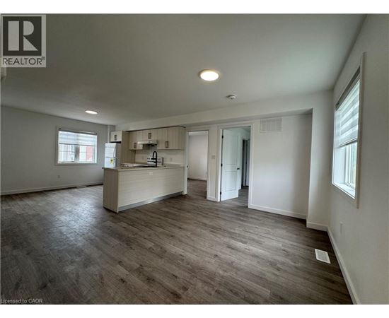 A spacious room with a wooden floor and white walls.